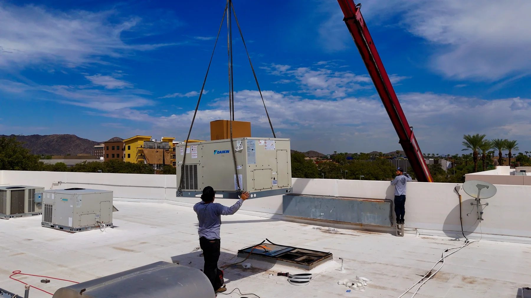 Packaged Daikin rooftop HVAC unit suspended from crane rigging
