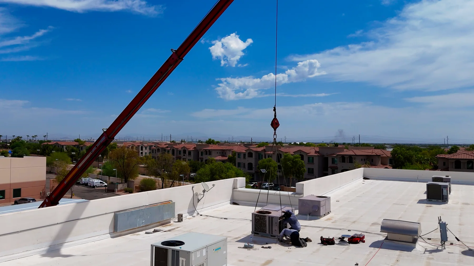 Red crane above packaged rooftop HVAC units during a commercial project