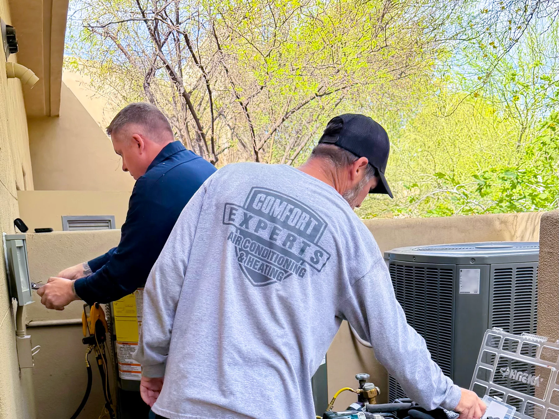 Comfort Experts team working beside an outdoor air-conditioning system