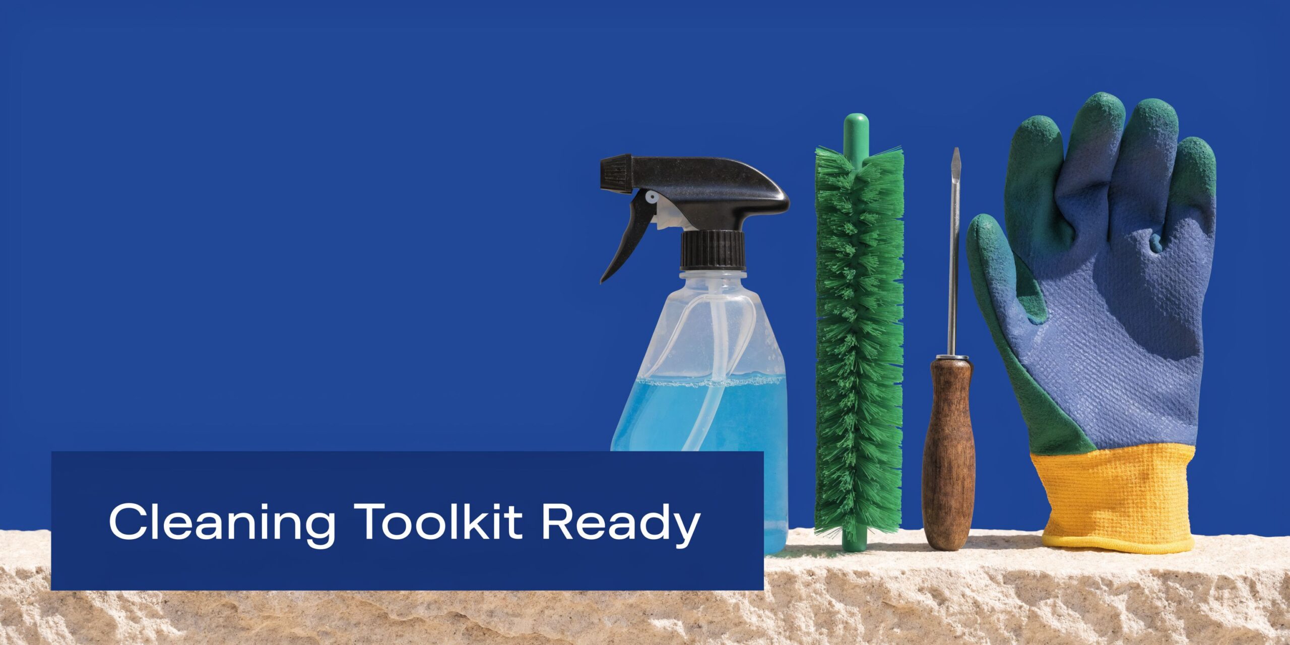 A spray bottle, a green brush, a screwdriver, and a glove placed on a stone surface.